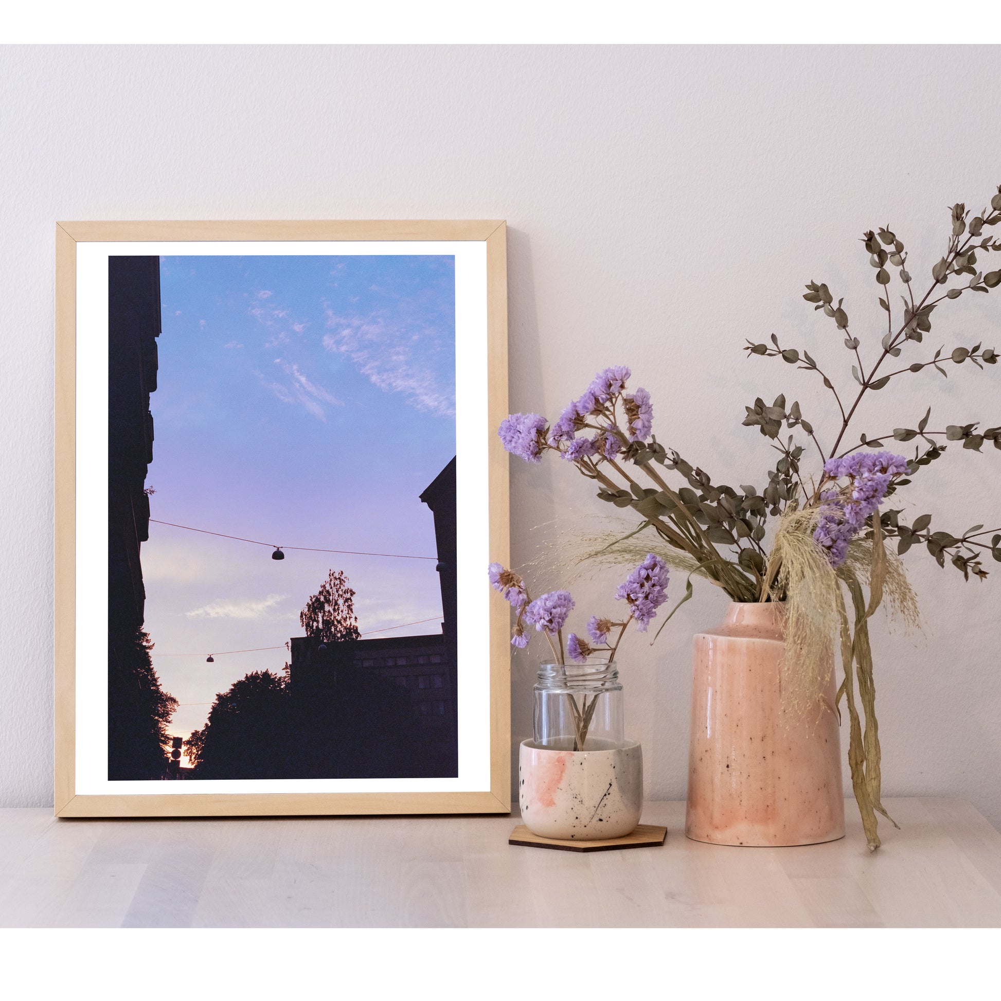 Detail of the 30x40 size photo in a frame, next to a ceramic pot with flowers. It is larger than the pot, and equal height to the flowers.