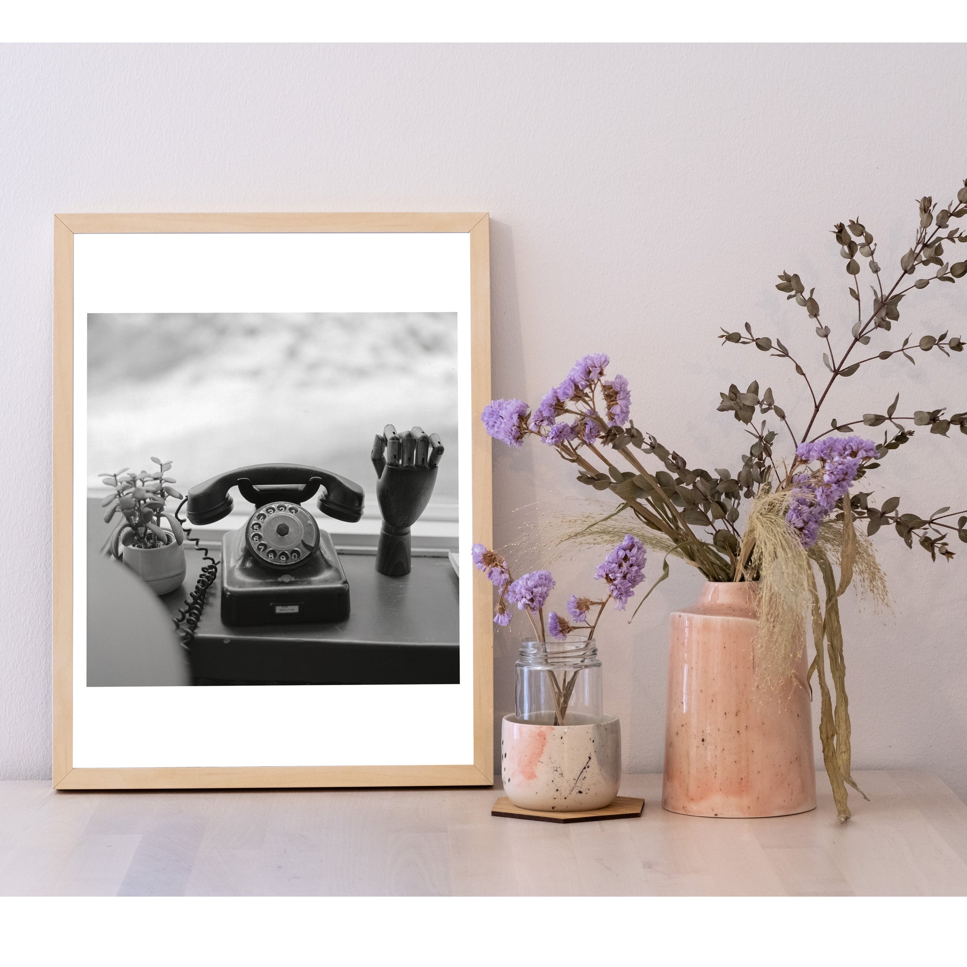 Detail of the 30x40 size photo in a frame, next to a ceramic pot with flowers. It is larger than the pot, and equal height to the flowers.
