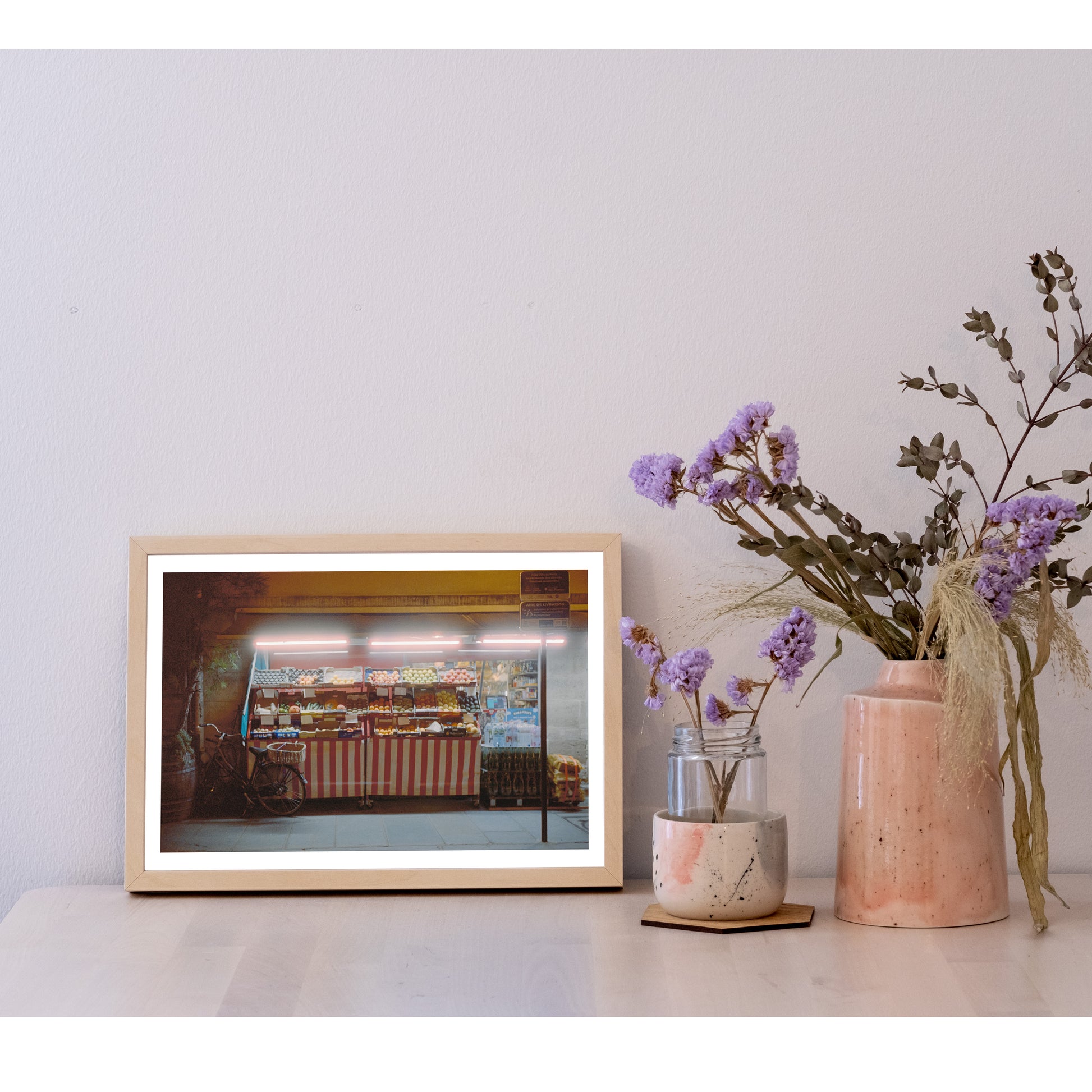 Detail of the 21x30 size photo in a frame, next to a ceramic pot with flowers. It is larger than the pot, and half the height of most of the flowers. In width, it is two and a half pots next to each other.